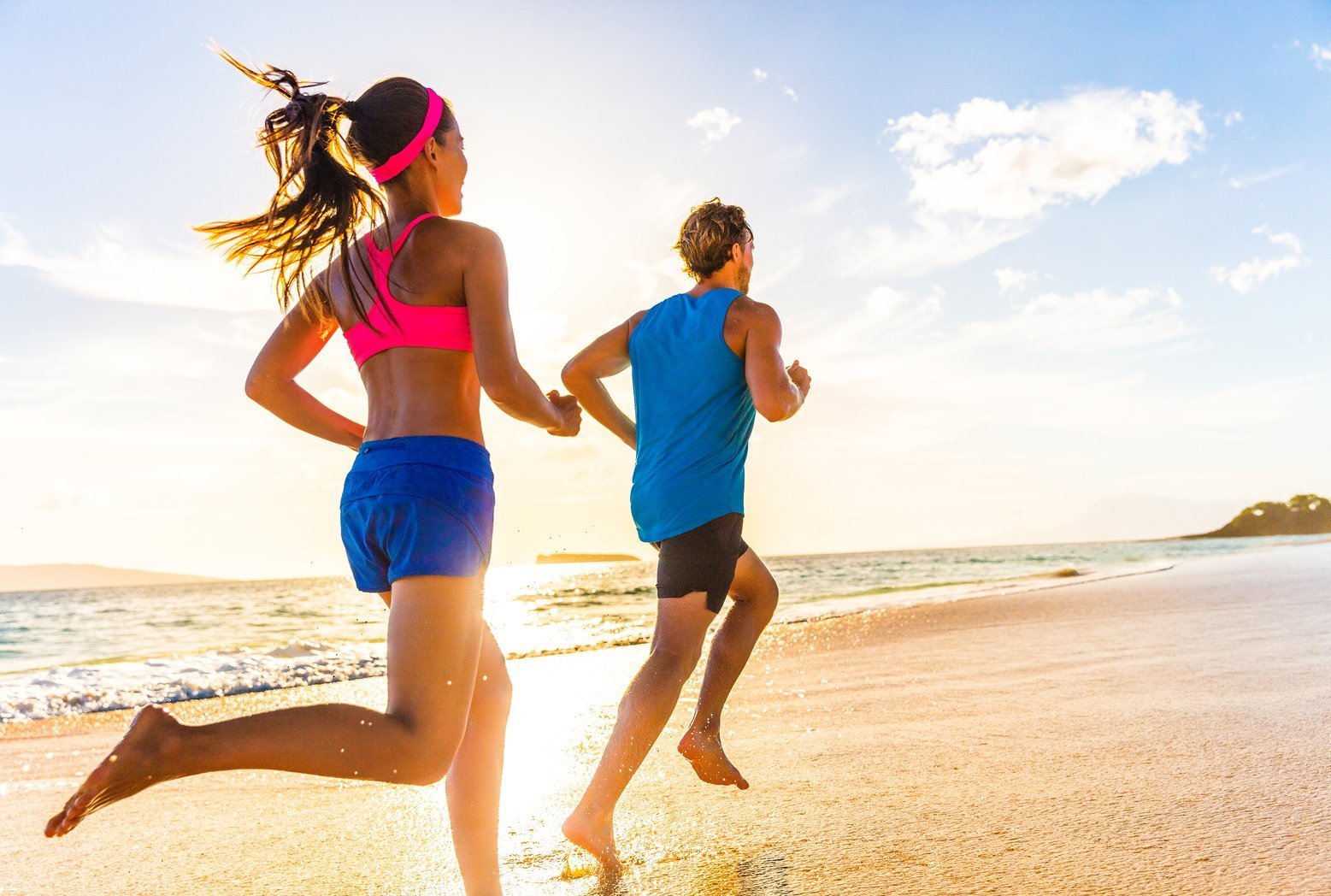 Woman and Man running on the beach in the sunset trying to get in shape for summer